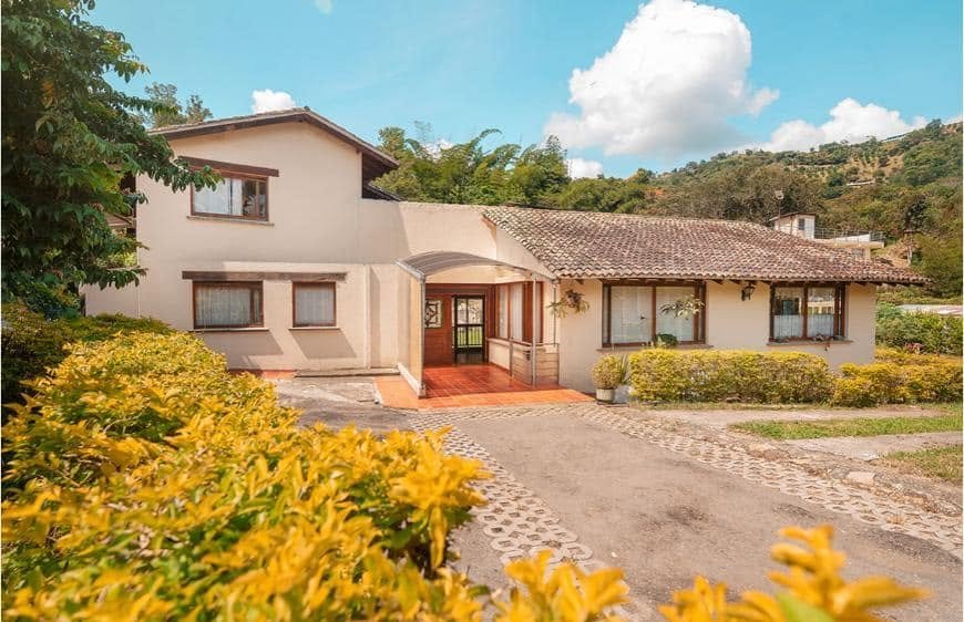 Entrada de la casa de El Campestre con jardín de flores amarillas